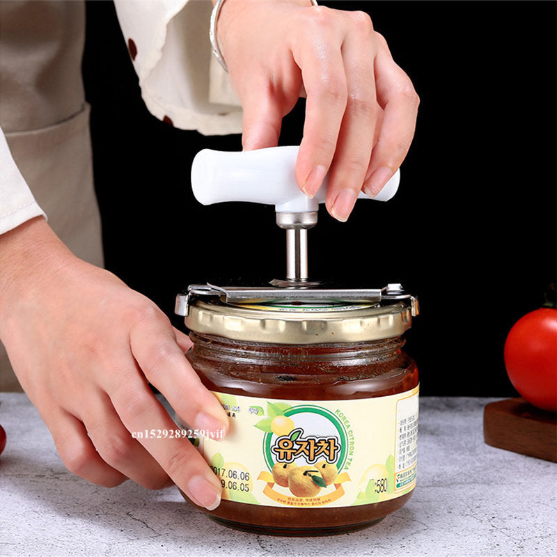 Person using a jar opener on a jar with a label, tomato in the background