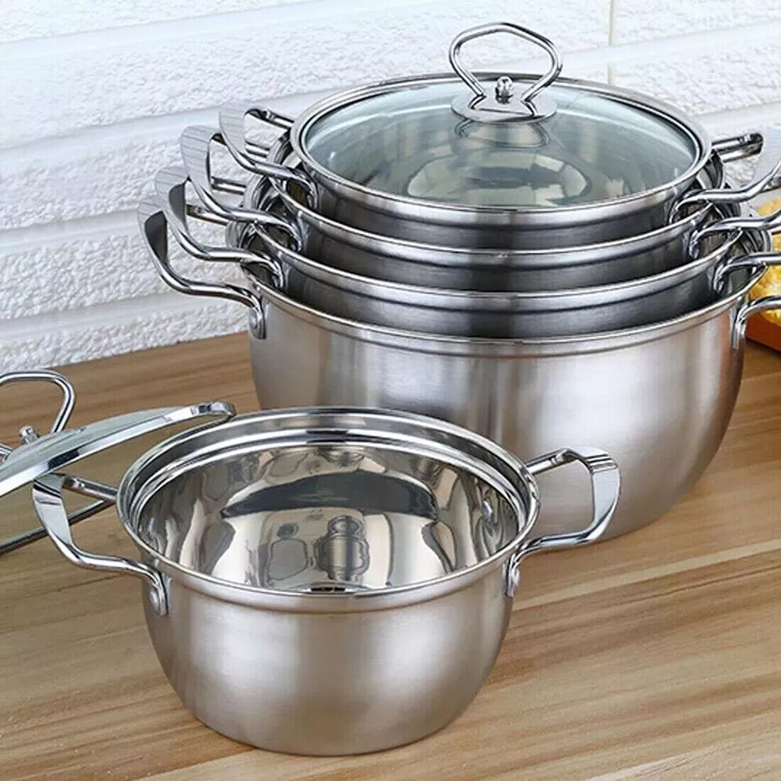Set of stainless steel pots with lids on a wooden surface