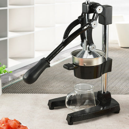 Black manual juicer with a glass on a light surface