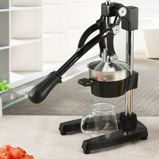 Black manual juicer with a glass on a light surface