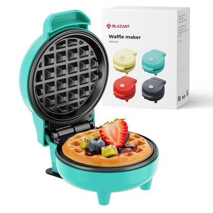 Turquoise waffle maker with a cooked waffle and fruit toppings, next to its packaging.