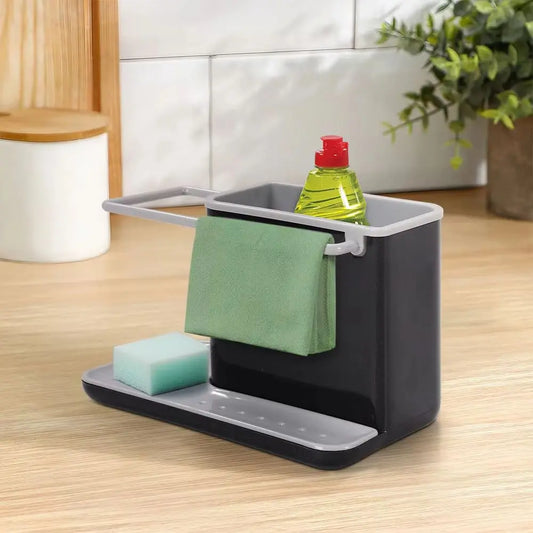 Kitchen sink caddy with sponge, cloth, and bottle on a wooden countertop.