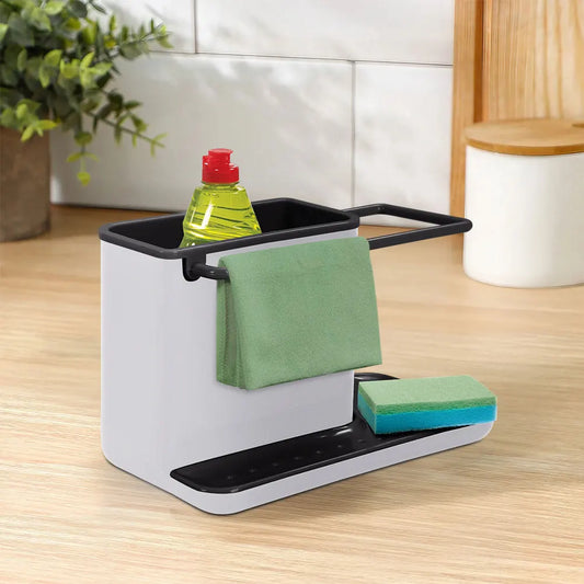 Kitchen sink caddy with sponge, towel, and bottle on a wooden countertop.