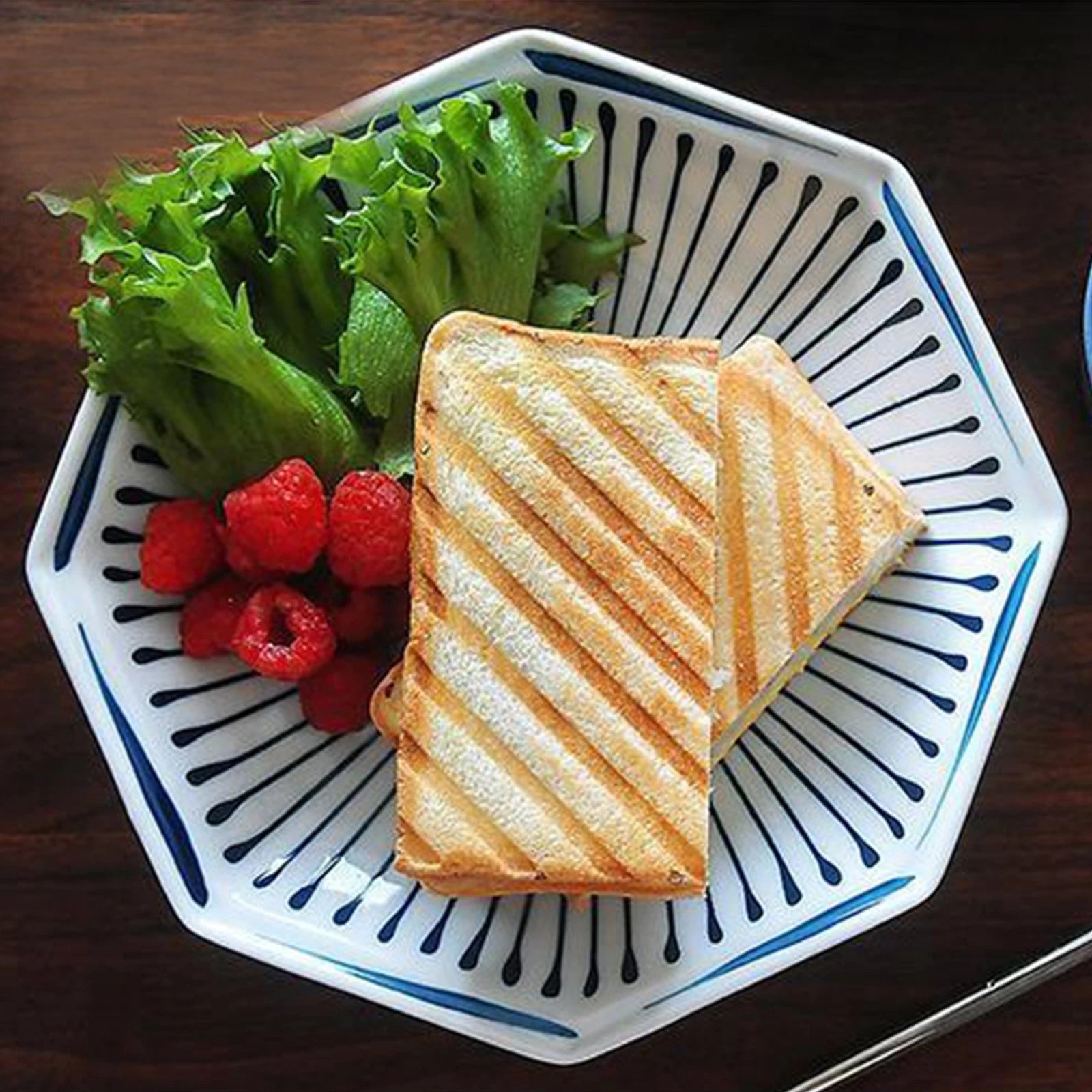 Grilled sandwich with lettuce and raspberries on a decorative plate