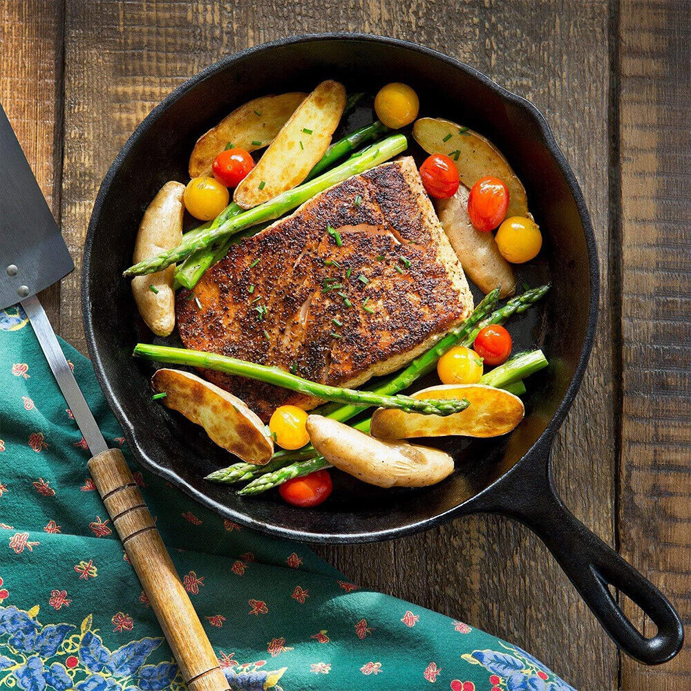 Fried fish with vegetables in a cast iron skillet on a wooden surface