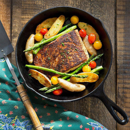 Fried fish with vegetables in a cast iron skillet on a wooden surface